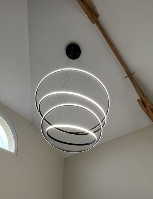 Luminaire LED suspendu design composé de plusieurs anneaux lumineux installés au plafond d’une maison.
